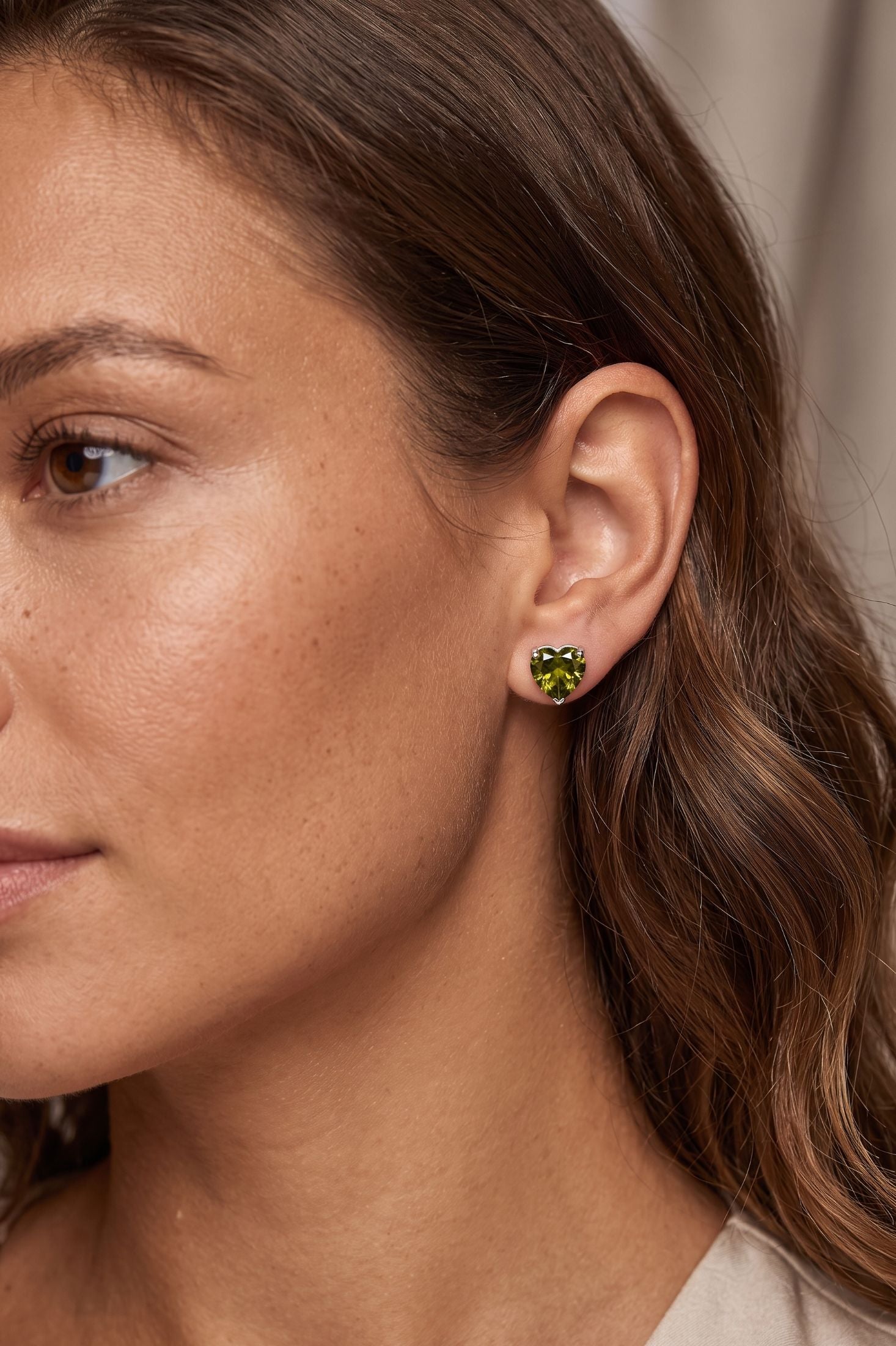 Angled view of Amore Heart Peridot Stud Earrings Silver, showing heart design, peridot detailing, silver finish and the jewellery profile.