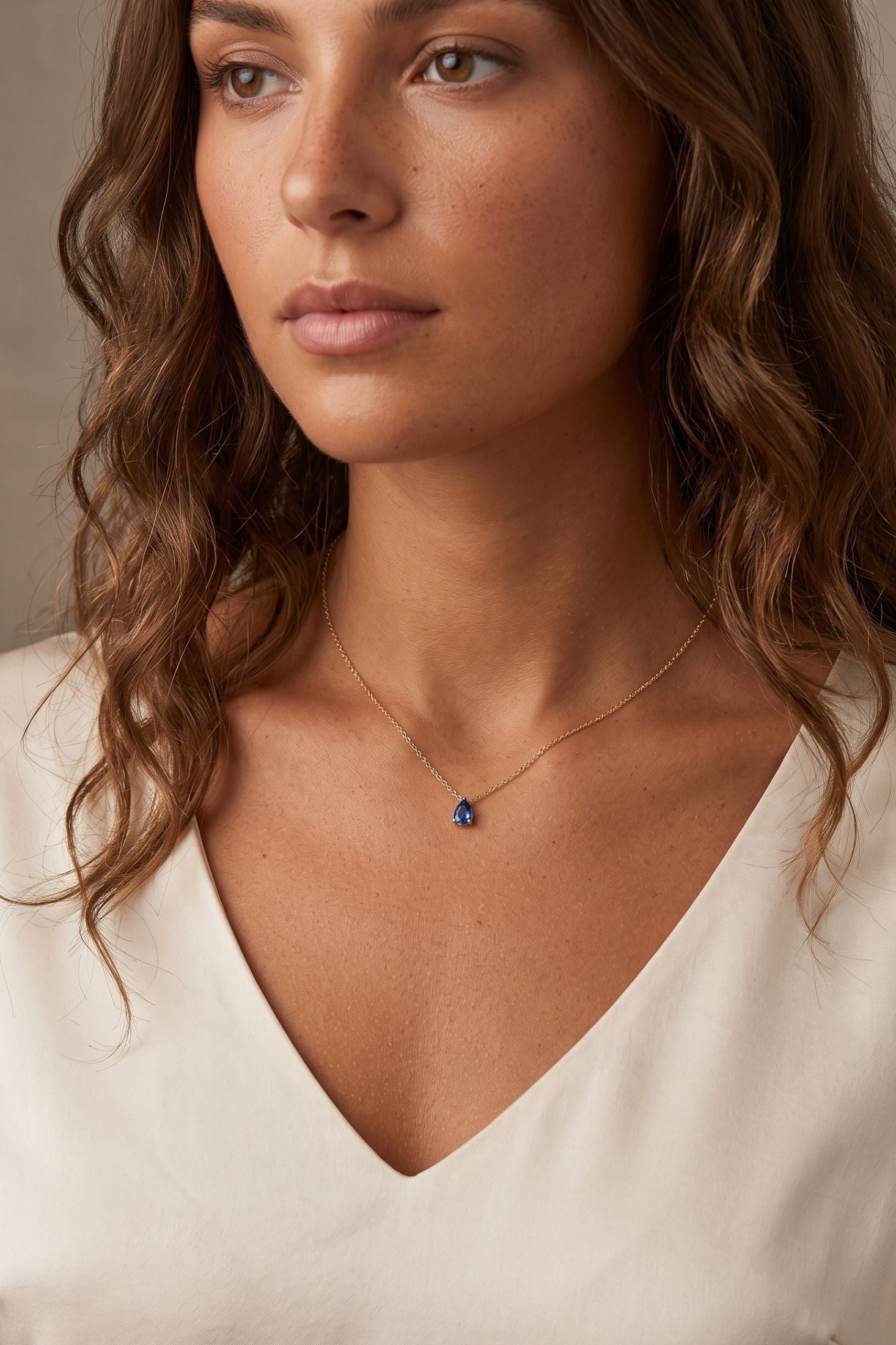 Angled view of Adele Teardrop Necklace Gold Blue Topaz, showing blue topaz detailing, gold finish and the jewellery profile.