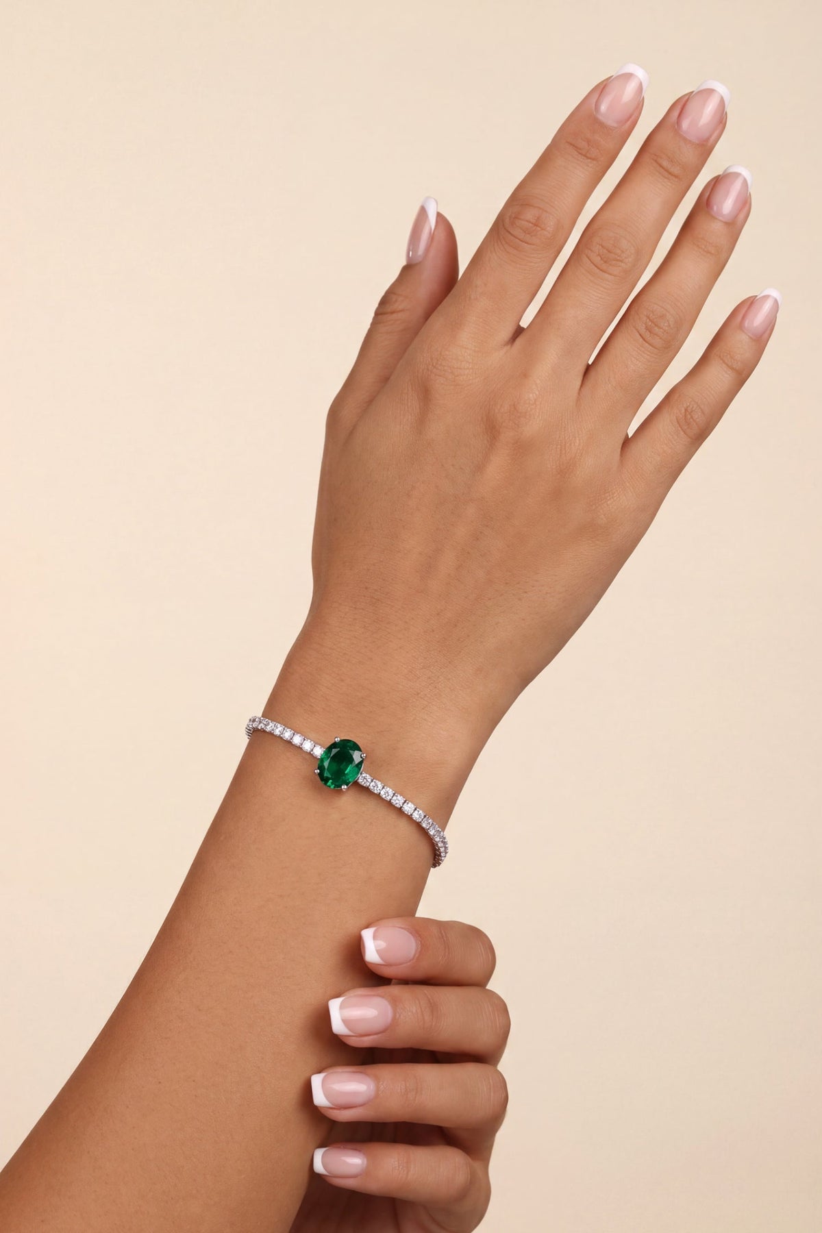 Elegant silver tennis bracelet featuring a vibrant green emerald center stone.