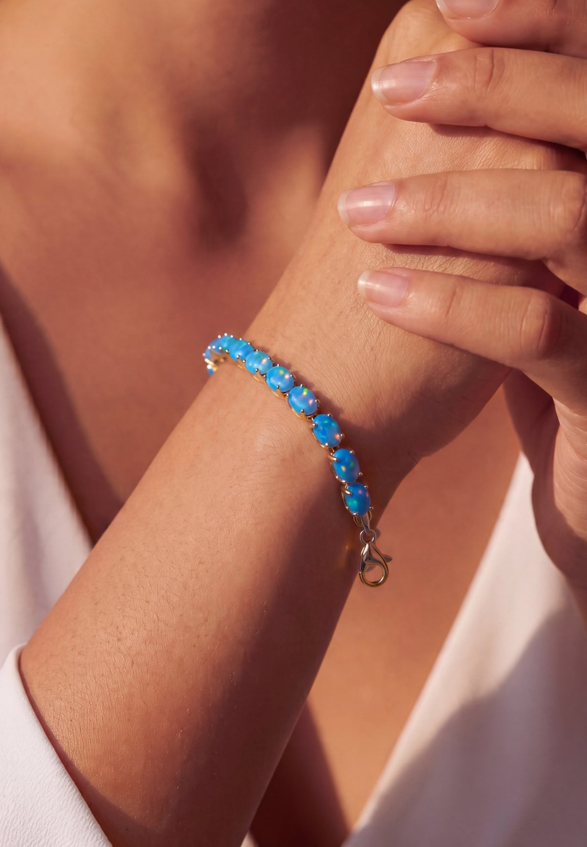 Woman wearing a gold bracelet with iridescent blue opal gemstones