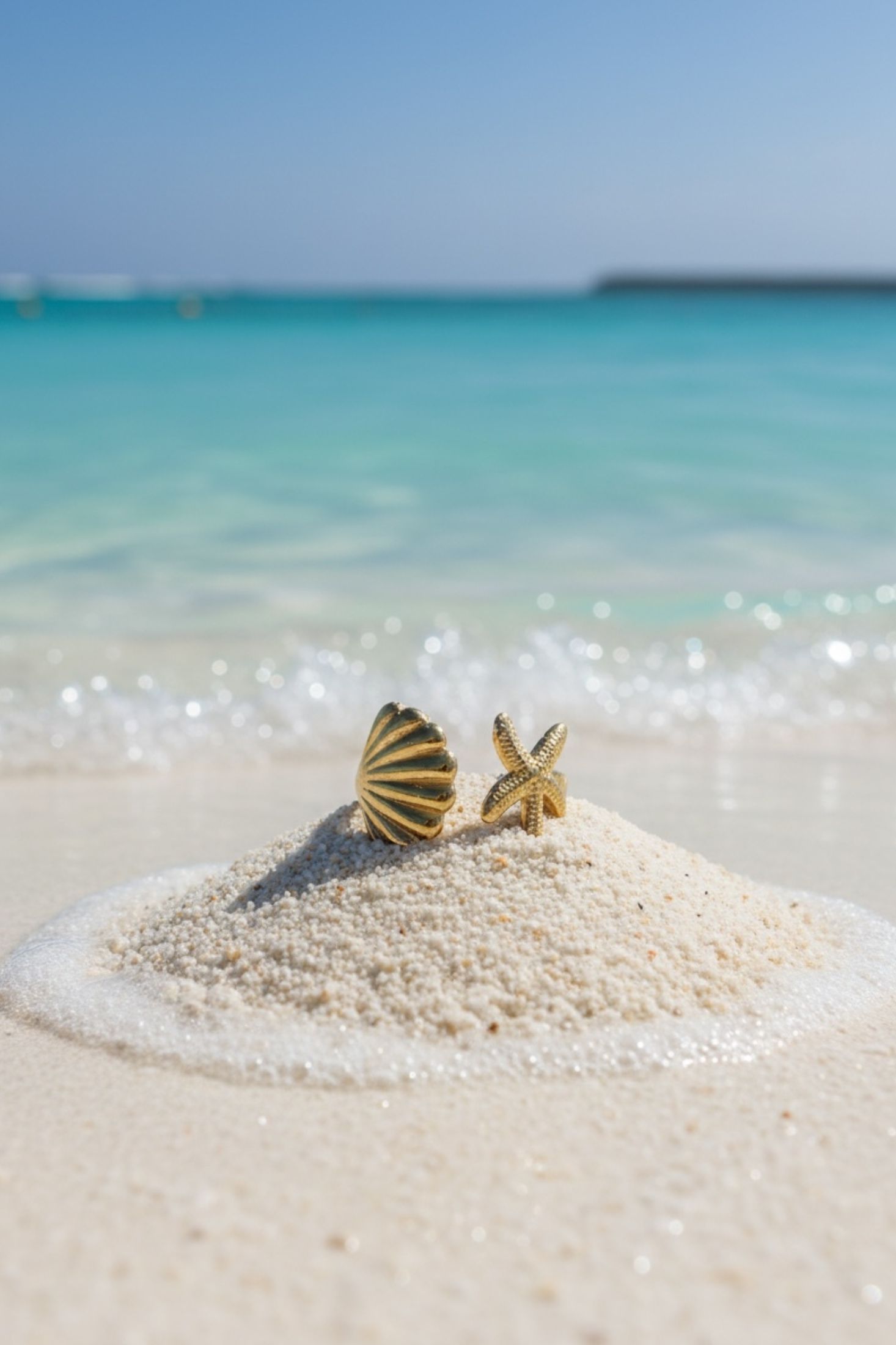 A gold ring with a starfish and shell  on a clear blue water background