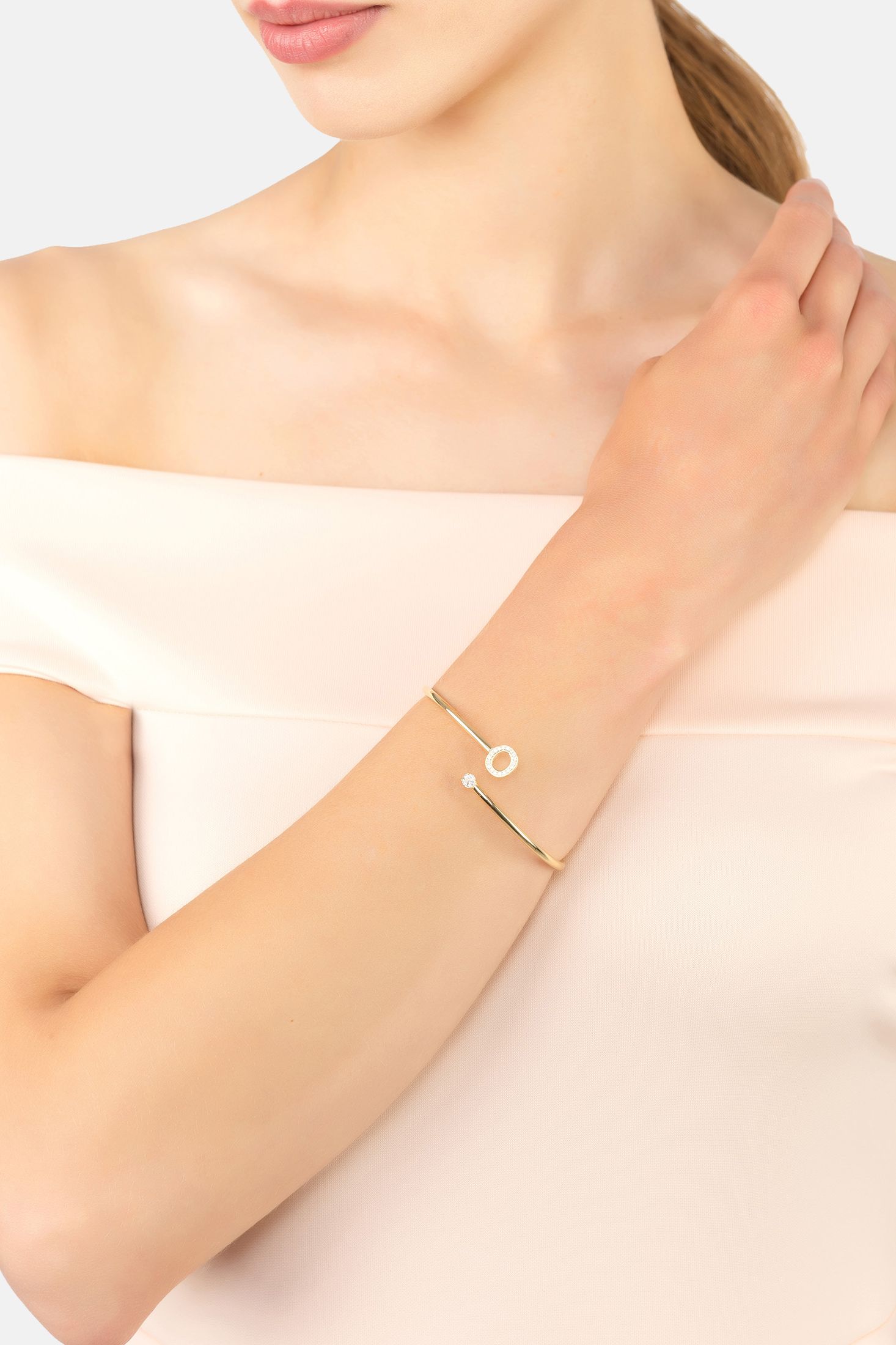 Gold bracelet on a person's wrist with a plain background