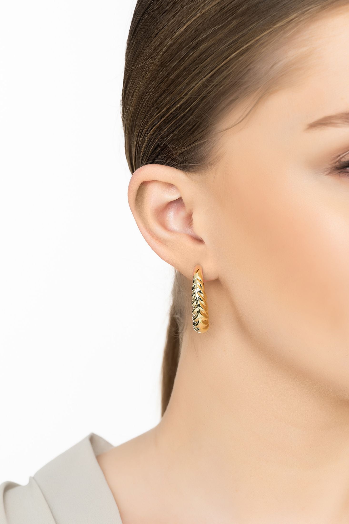Angled view of Twirl Harmony Hoop Earrings Gold, showing gold finish and the jewellery profile.