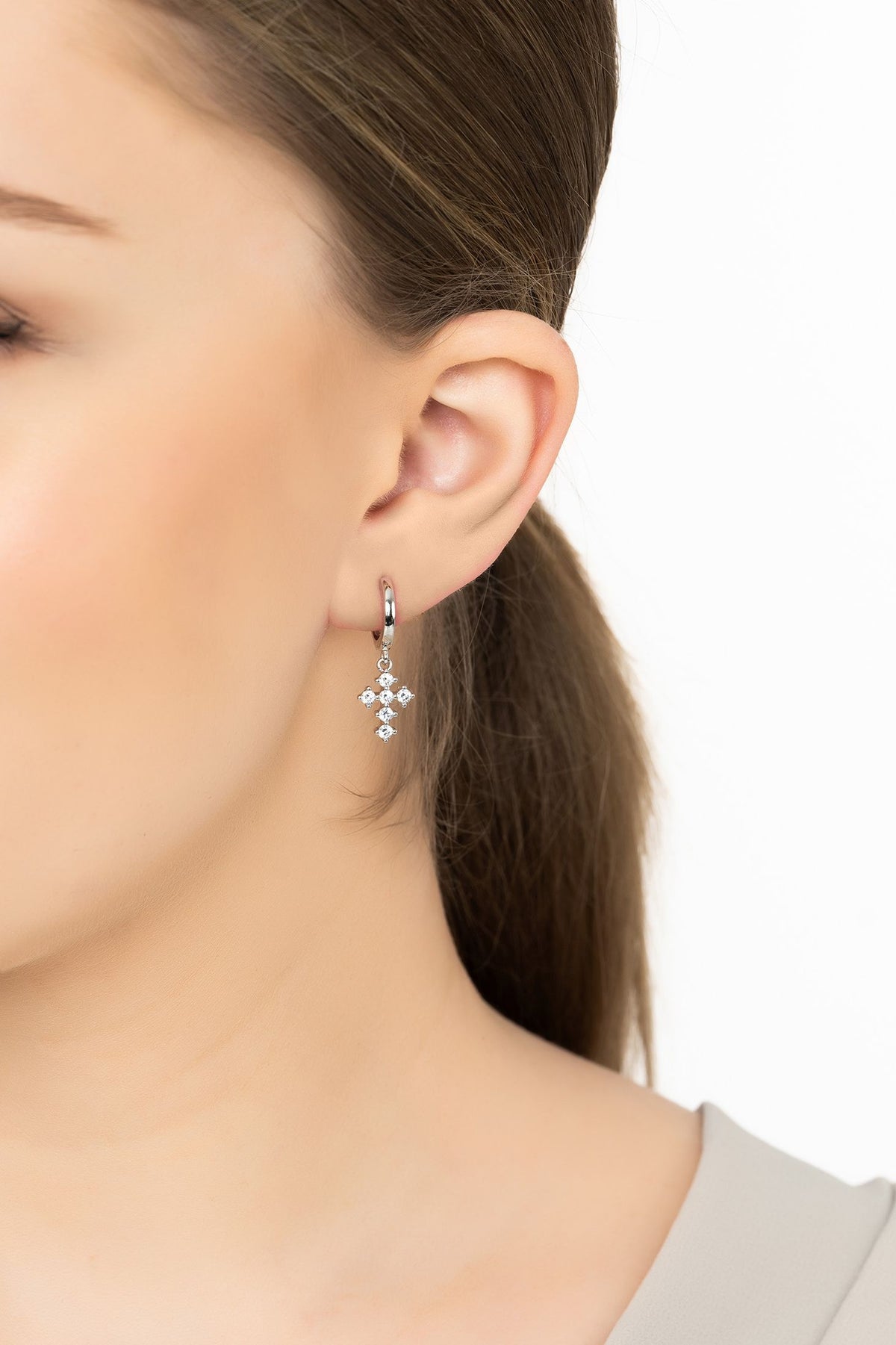 Angled view of Divina Fashion Huggie Hoop Earrings Silver, showing silver finish and the jewellery profile.