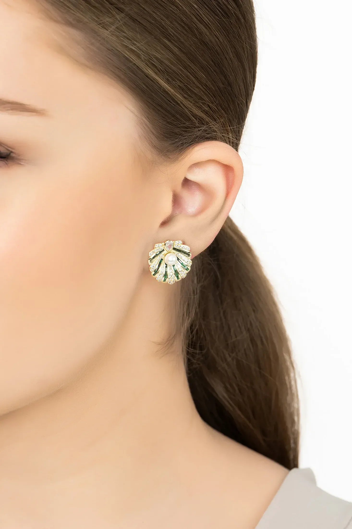 Angled view of Art Deco Scallop Shell Earrings Emerald Green With Pearl Gold, showing shell design, pearl and emerald detailing, gold finish and the jewellery profile.