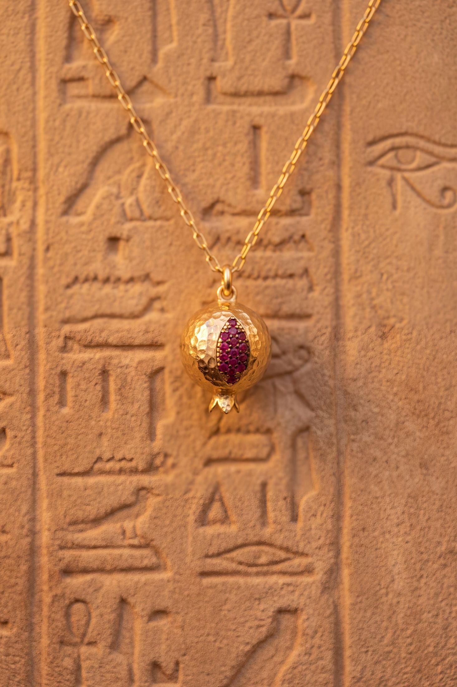 Angled view of Pomegranate Charm Necklace Gold, showing gold finish and the jewellery profile.