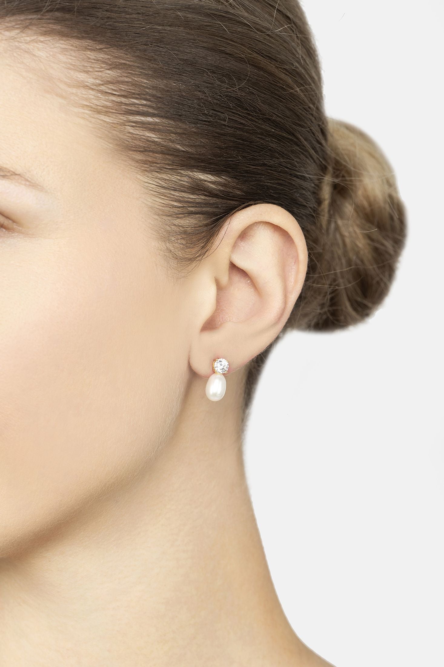 Pearl earring worn by a person on a plain background