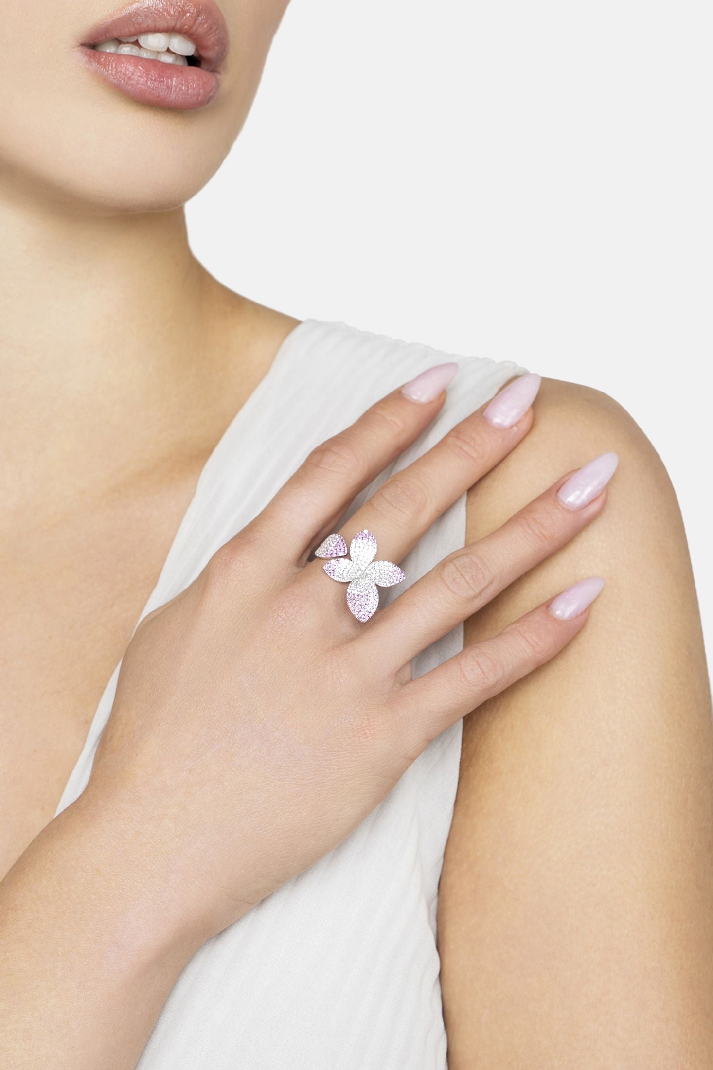 Close-up of a hand wearing a pink flower ring on a white background