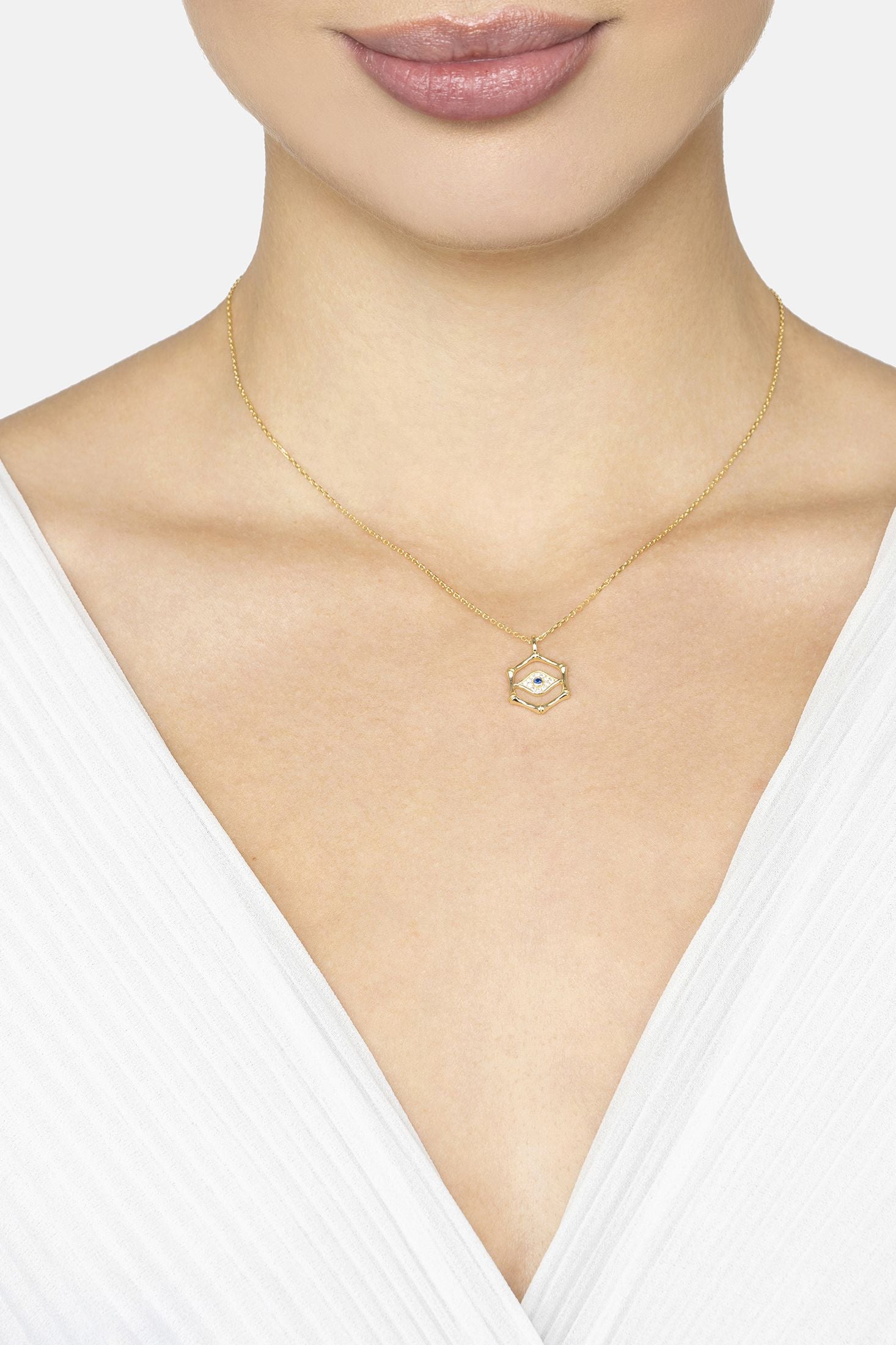 Gold necklace with a pendant on a model wearing a white top