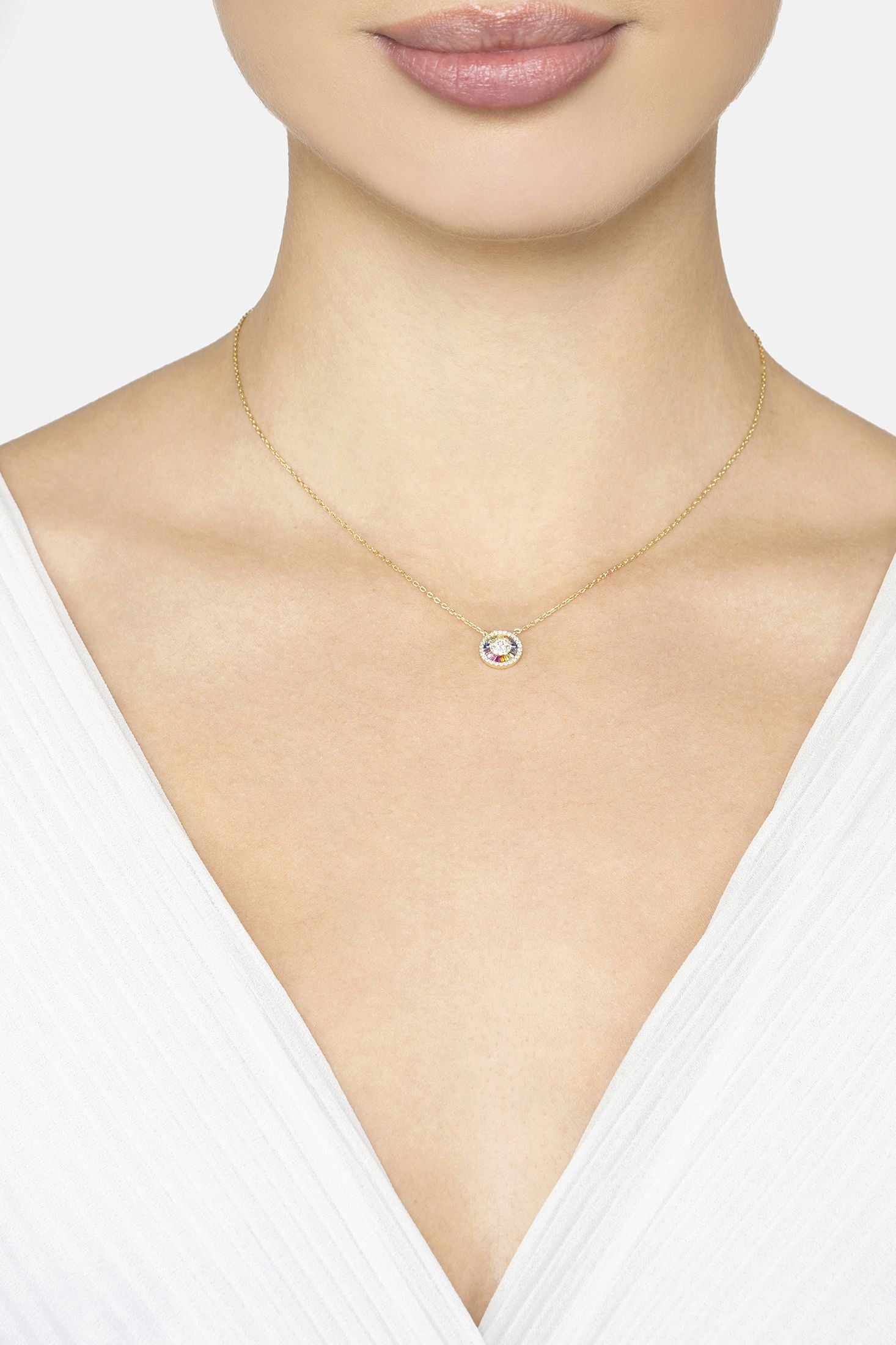 Necklace with a small round pendant worn by a person in a white top.