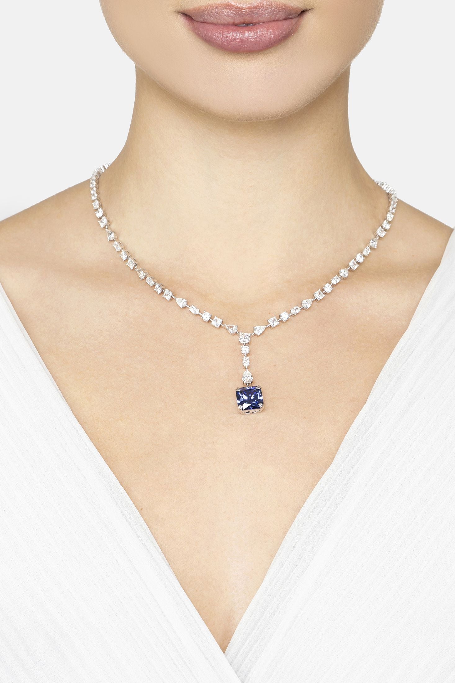 Diamond necklace with a central blue gemstone worn by a model on a white background