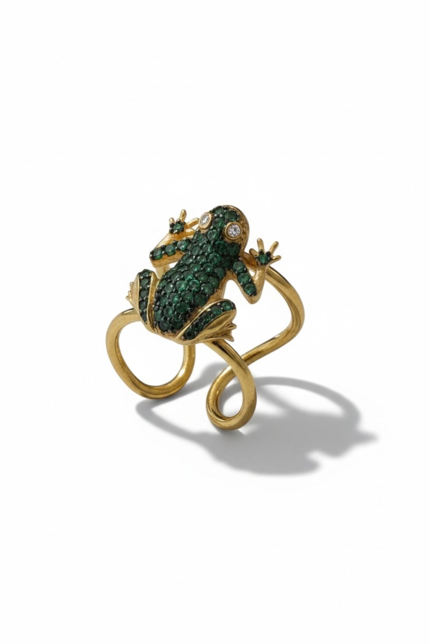 Gold frog-shaped ring with green gemstones on a white background