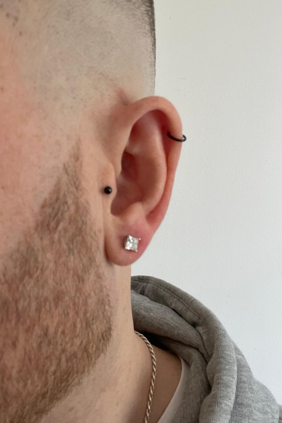 Mens Single Square Solitaire Stud Earring Moissanite Silver worn by a model, showing how they sit on the ear and their scale.