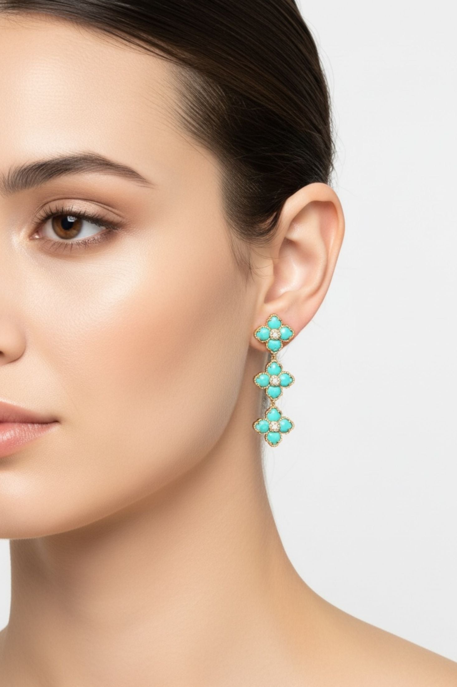 Close-up of a woman wearing turquoise floral earrings against a neutral background