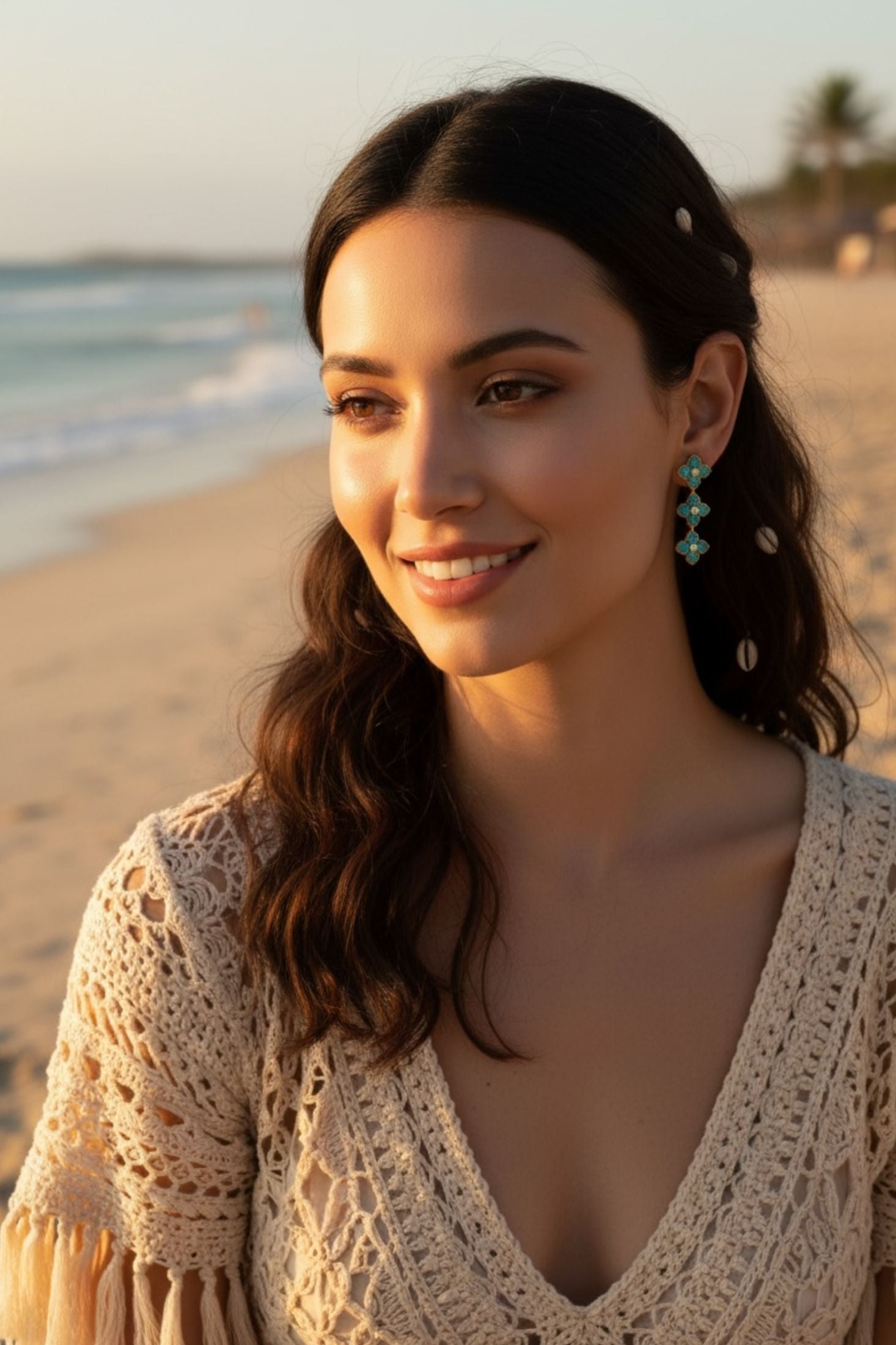 Woman on a beach wearing turquoise clover earrings with a scenic background