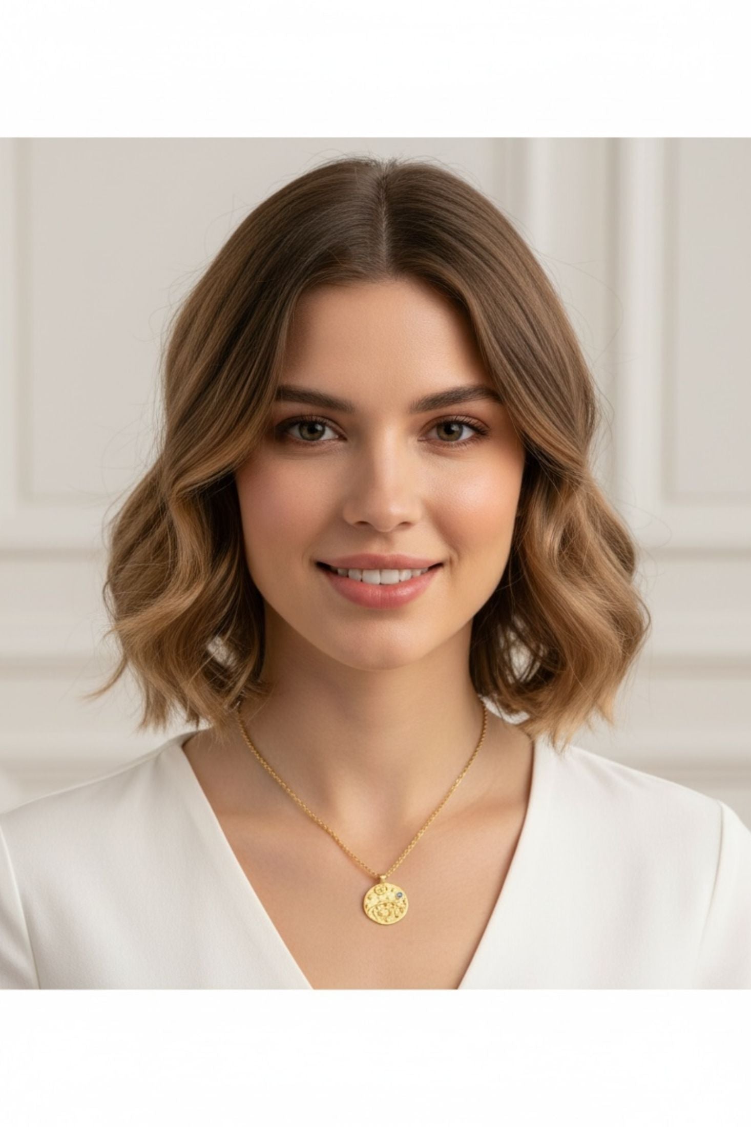 Woman wearing a gold necklace with a pendant against a white background