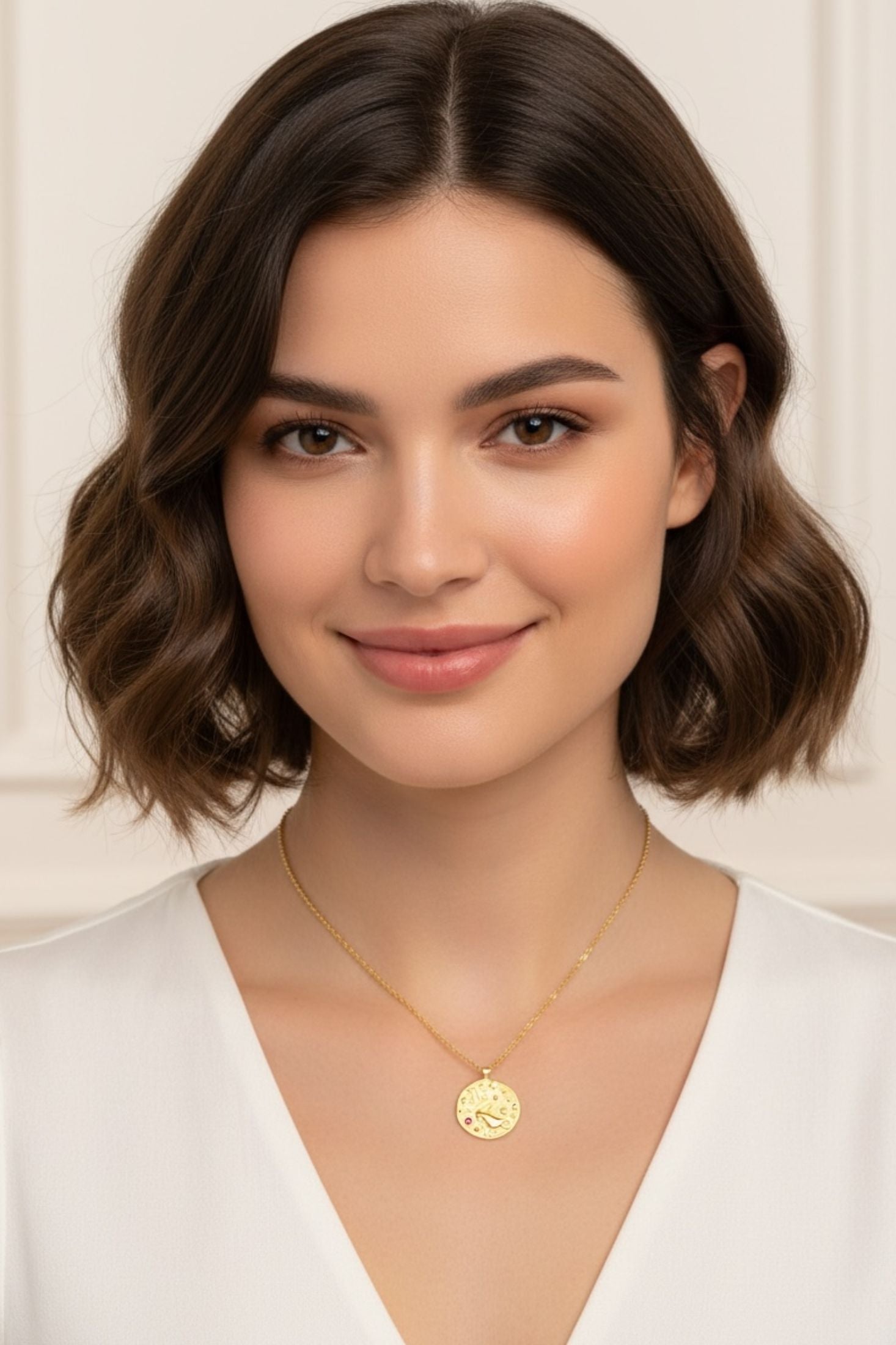 Gold pendant necklaces worn by a model.