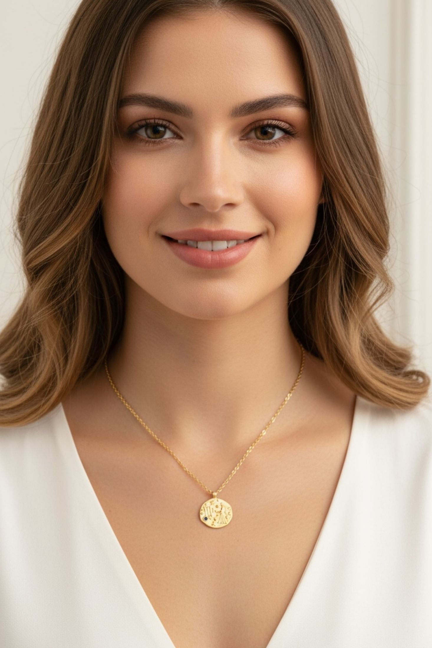 Woman wearing a gold necklace with a beige background
