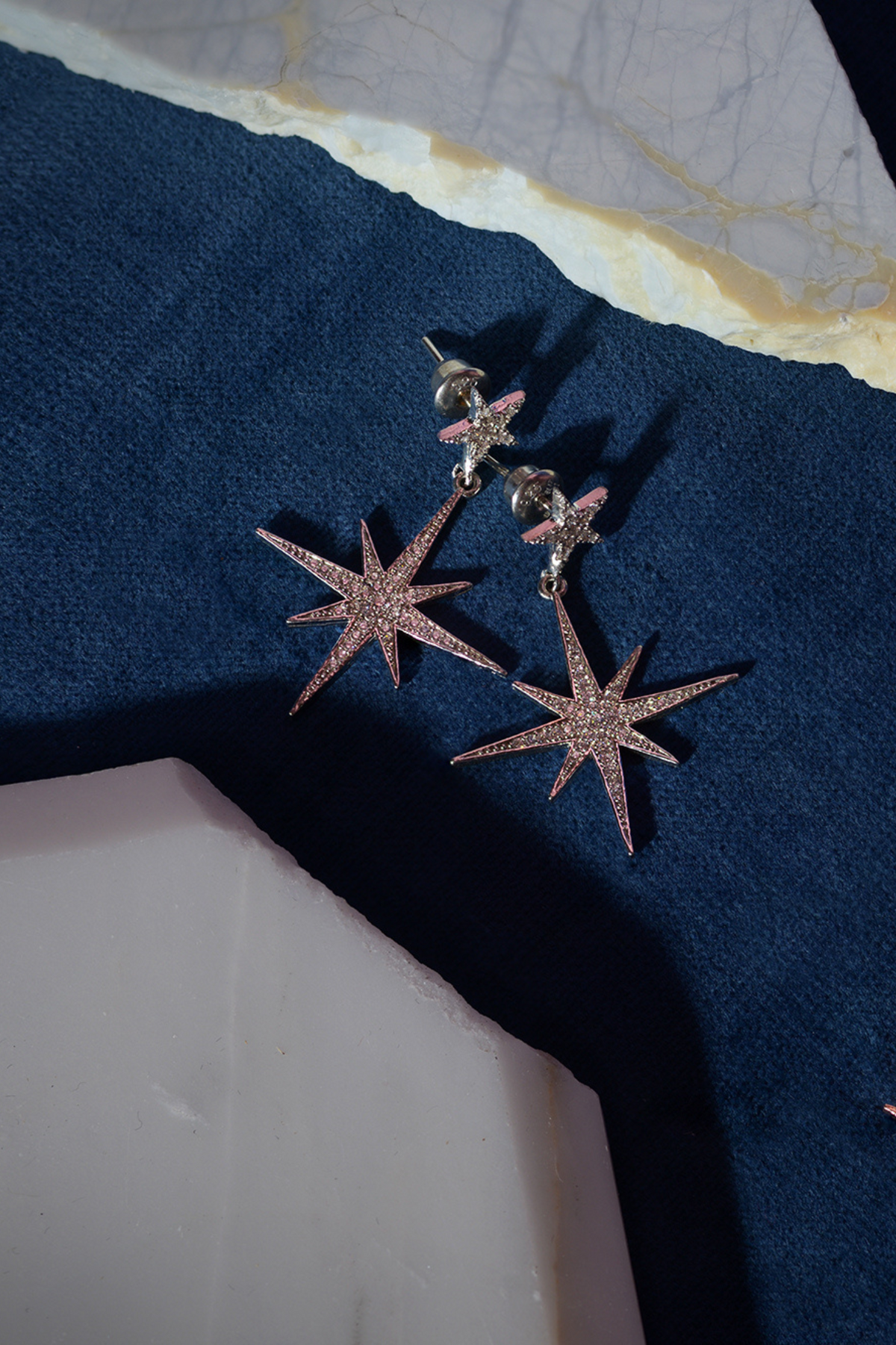 Petite Star Burst Drop Earrings Rose Gold worn by a model, showing how they sit on the ear and their scale.
