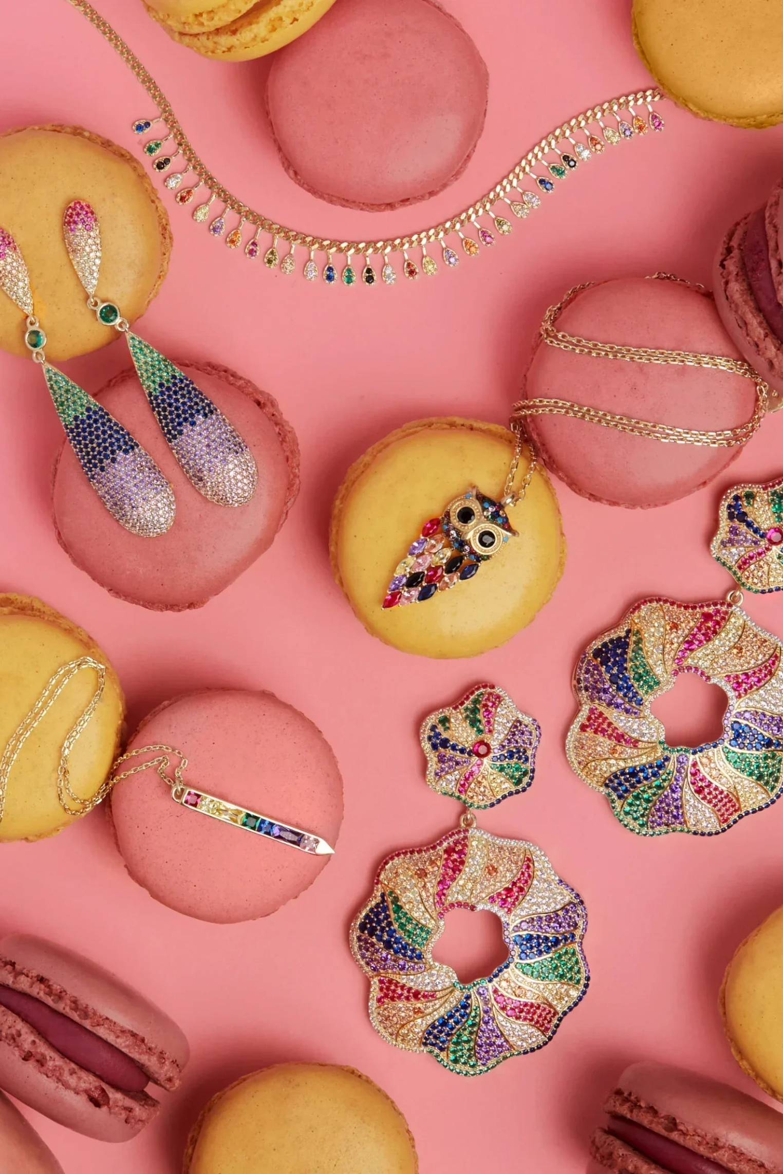 Colorful jewelry and macarons on a pink background